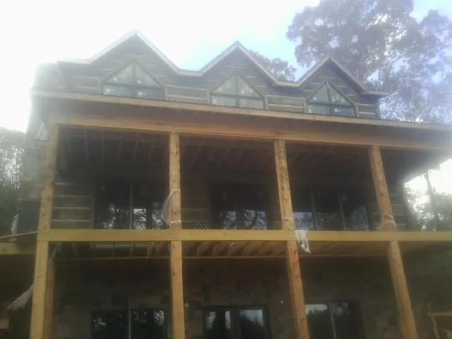 Dormers and porch framing on a large log home under construction — Roof Coating work by our crew in Temperance