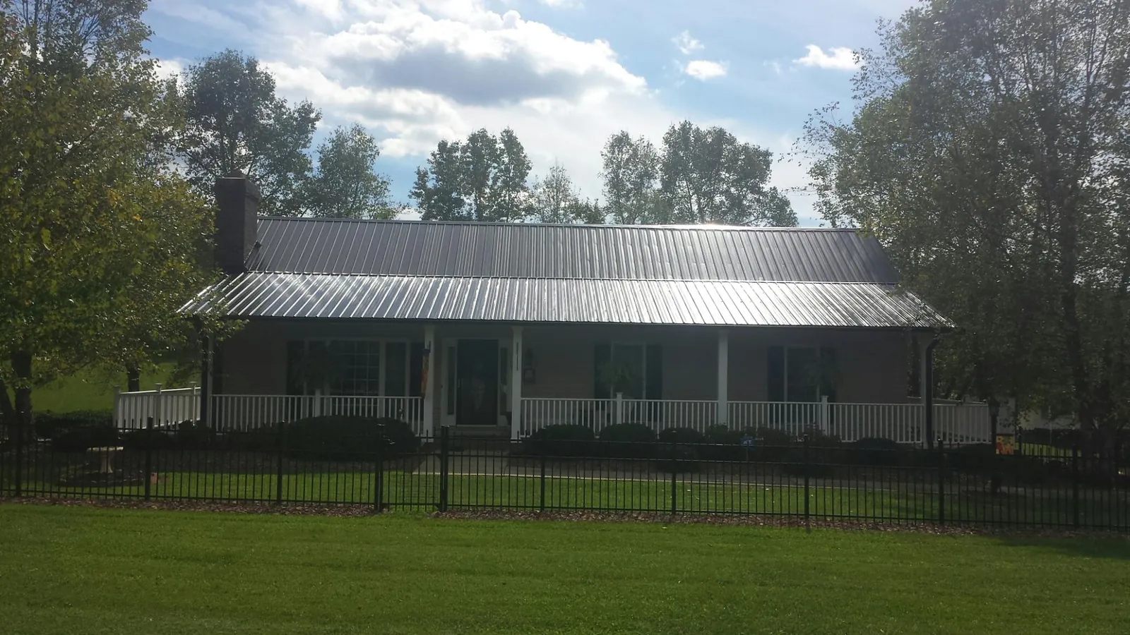 Gray metal roof on a brick ranch with a full width front porch — Gutter Guard Installation work by our crew in Temperance