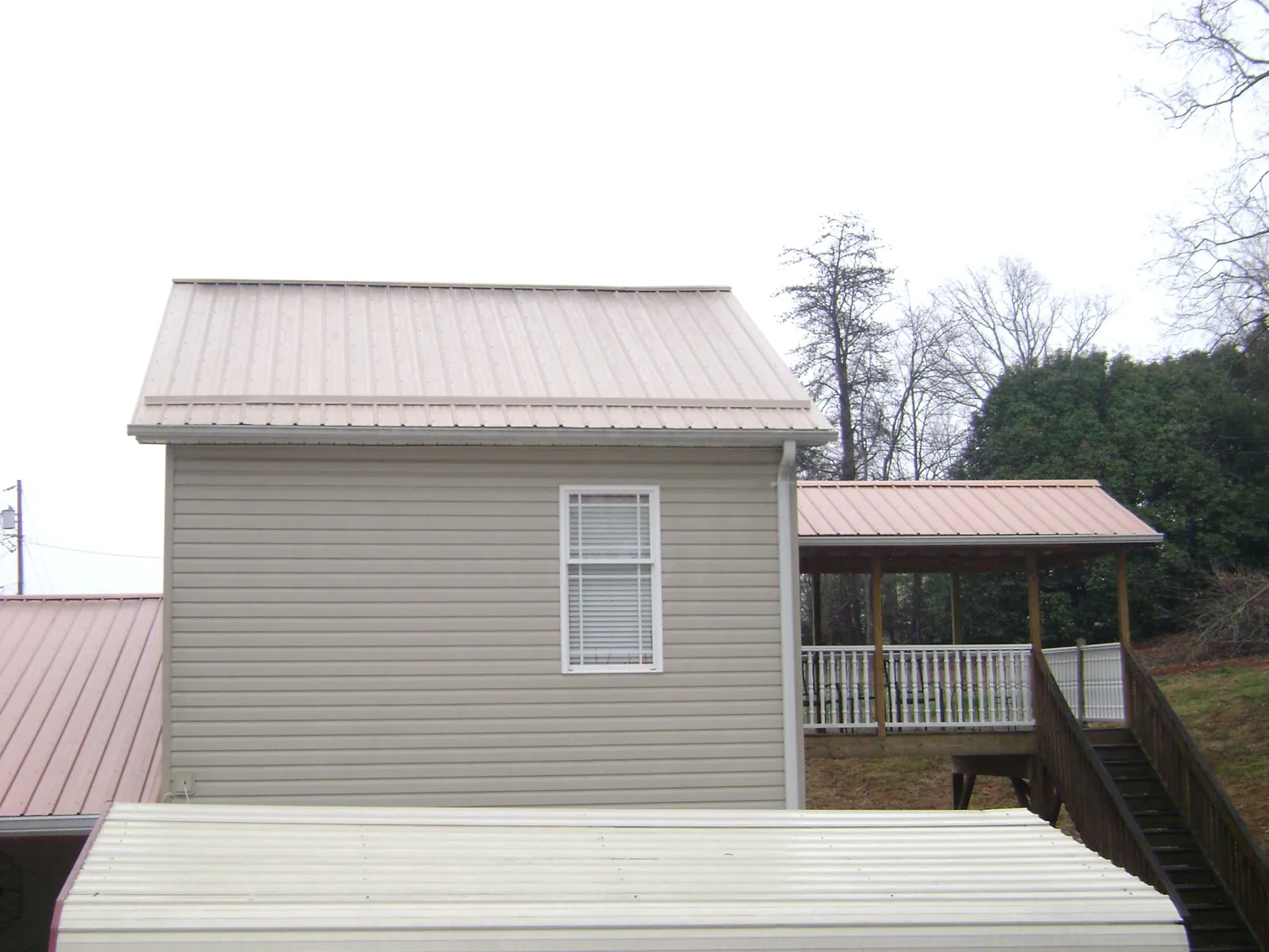 Tan metal roofs on a two story addition and attached porch, from a Roof Replacement job in Temperance